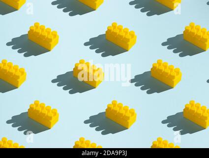 Seamless pattern of yellow cubes for children's construction. Parts of the constructor. Side view, blue background, shadows. Stock Photo
