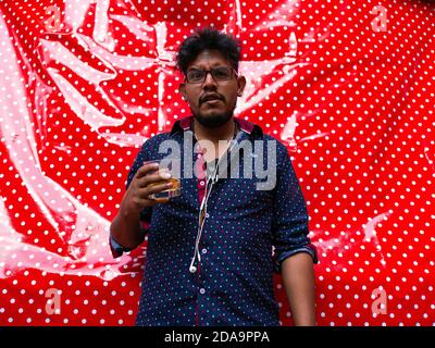 LA PAZ, BOLIVIA - Jun 21, 2013: La Paz / Bolivia - June 20 2013: Hispanic Male in Blue Shirt with Glasses Holds a Drink in his Right Hand and Looks Su Stock Photo