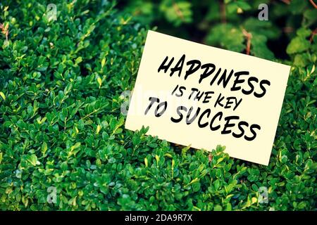 Motivational inspirational quote happiness is the key to success written on paper in a garden with green plants. Stock Photo