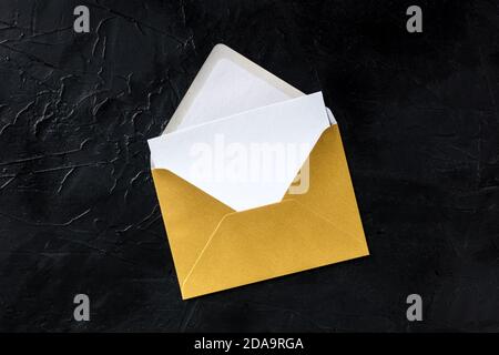 Greeting card in a golden envelope mockup, shot from above on a black background with copy space Stock Photo