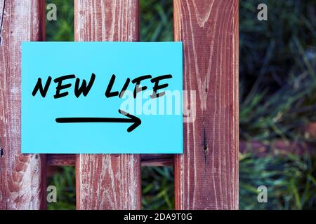 New life with destination arrow written on paper on a fence in nature. Starting or beginning a new life concept. Stock Photo