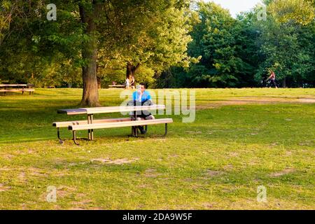 Montreal, Canada - June, 2018: Young Canadian male sits on a wooden bench in Mount Royal Park in Montreal, Canada. Stock Photo