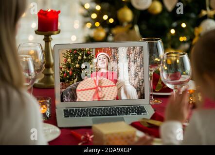A happy family with a child is celebrating Christmas with their friends on video call using webcam. Family greeting their relatives on Christmas eve Stock Photo