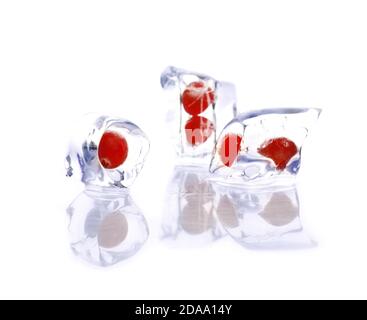 Closeup of three ice cubes with cherries inside isolated on a white background Stock Photo