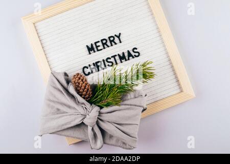 Christmas eco-friendly gift box furoshiki. Lightbox with text Merry Christmas. Zero waste concept. Stock Photo