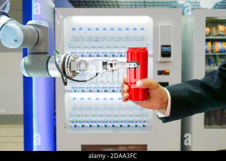 Close-up industrial robotic gripping red soda can for sending to businessman via smart automatic beverage dispenser machine service Stock Photo