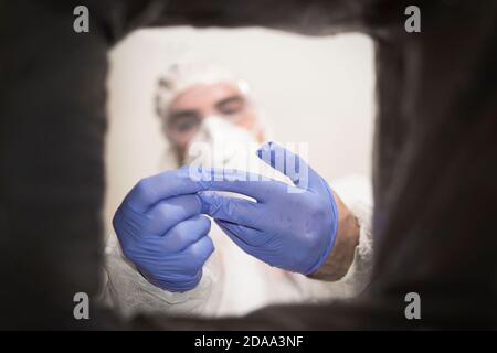 Closeup cropped portrait, healthcare professional throwing away blue disposable latex gloves in trash. Infection control protocol. Stock Photo