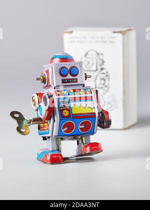 The tin toy robot is walking against the background of the cardboard packaging Stock Photo