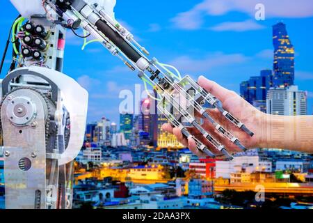 AI Robot handshake with human for join on teamwork on blurred building construction on blue tone color background Stock Photo