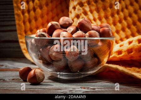 hazelnuts in a glass cup on a yellow textile background Stock Photo