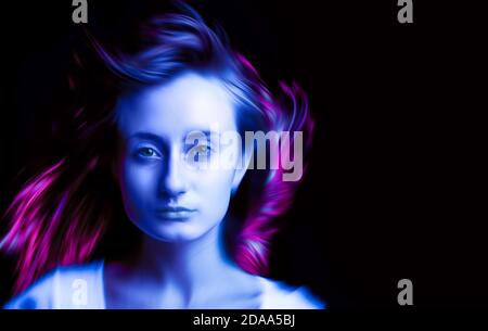 Woman in colorful bright neon blue and purple lights posing in studio, beautiful girl, trendy colors. Vivid neon colors. Blurred hair on a dark backgr Stock Photo