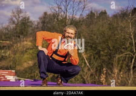 Fix or build. Roofer repair roof. Roof installation. Bearded man work outdoor. Roof Mechanic concept. Inspect repair and replace. Assemble temporary equipment or structures. Structural sheathing. Stock Photo