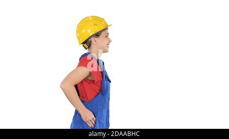 Young woman in yellow hardhat walking on white background. Stock Photo