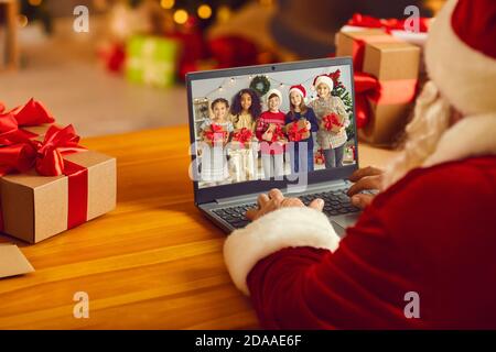 Santa Claus having video call with group of diverse kids using laptop computer in his workshop Stock Photo