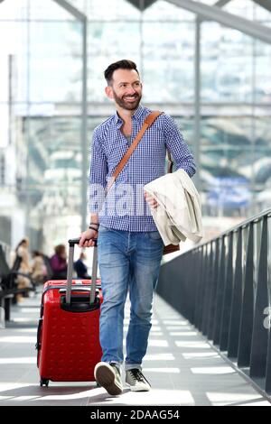 Full body portrait of handsome mature man traveling with suitcase Stock Photo