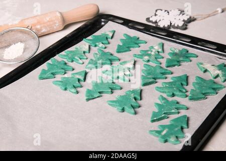 Christmas cakes laid out on a baking sheet before baking in the form of Christmas trees Stock Photo