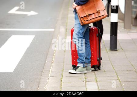 Side view portrait of male traveler standing by the street with suitcase Stock Photo
