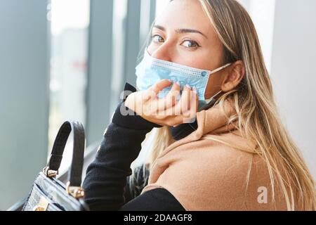 Young woman with face mask due to Covid-19 pandemic looks fearful and worried Stock Photo