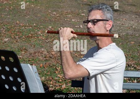 A new Yorker plays yje Chinese bamboo flute the dizi, in a park in Flushing, Queens, New York City. Stock Photo