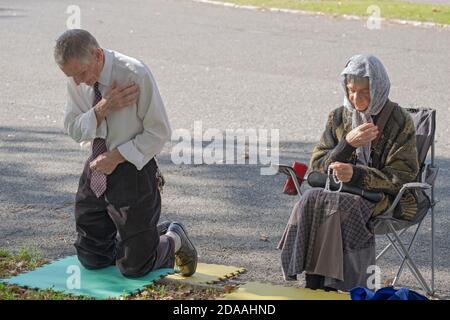 A devout Christian couple pray at the Vatican Pavilion site in Flushing Meadows park where Mary & Jesus appeared to Veronica Lueken. In Queens NYC. Stock Photo