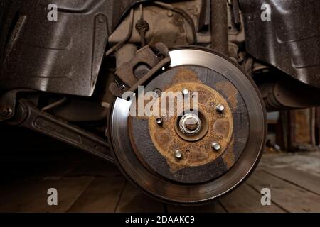 Closeup old, worn out and rusty car brake system. Rear disc brake of a car with a removed wheel. Stock Photo