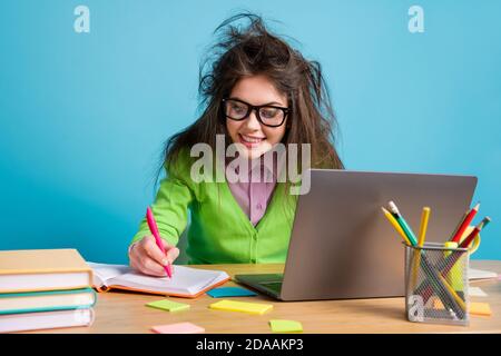 Close-up portrait of nice attractive intelligent cheery focused brunette girl doing homework using laptop isolated over bright blue color background Stock Photo