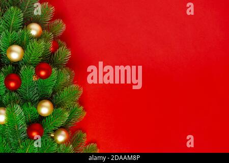 postcard from the branches of a Christmas tree with red and gold balloons on a rich background, copy space Stock Photo