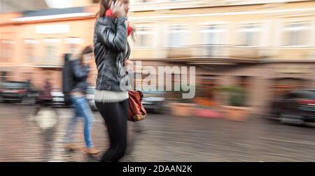 Abstract image of a young woman talking on a mobile phone on a city background. Intentional motion blur Stock Photo