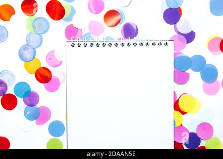 Festive, multicolored paper confetti in the form of circles and white open notebook isolated on white background Stock Photo