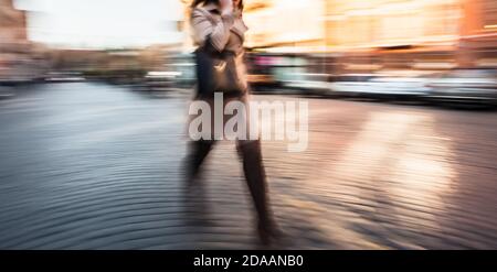 Abstract image of a young woman talking on a cell phone in a hurry. Intentional motion blur Stock Photo