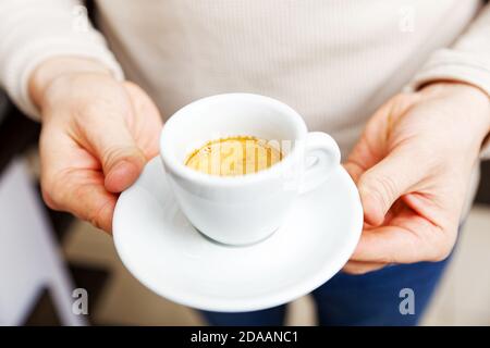 Closeup male hands holding a white cup of coffee espresso. Shallow focus. Stock Photo