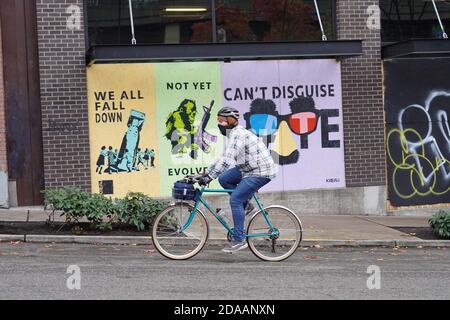 Seattle, United States. 10th Nov, 2020. A man wearing face mask rides a bicycle past boarded up windows in downtown. Credit: SOPA Images Limited/Alamy Live News Stock Photo