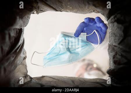 Throwing away single use medical face mask. Face mask after use. Environmental pollution by medical waste. Stock Photo