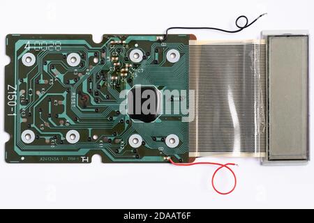 Electronic circuit board of a calculator with many electrical components and a red and black power lead. Isolated on white Stock Photo