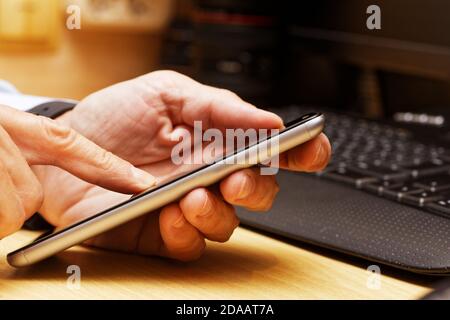 Human hands using smartphone. Finger swipe up and down the screen of smartphone. Warm light. Shallow focus. Stock Photo