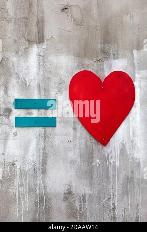 Blue equal sign and red wooden heart on a concrete wall Stock Photo