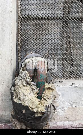 Rusty heat pipes with damaged insulation. Rusty heating system pipes with broken asbestos wrap insulation Stock Photo