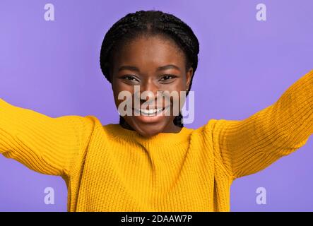 Joyful african american woman taking selfie, capturing self-portrait over purple background Stock Photo