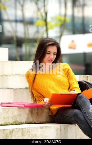 Portrait of attractive student sitting on steps studying Stock Photo