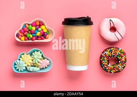 Cup of coffee, sweets and meringues in bowl in shape of cloud, chocolate with colorful topping and pink donut isolated on pink background Flat lay Top Stock Photo