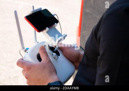 Close up of drone pilot hands controlling aircraft with remote control transmitter outdoors Stock Photo