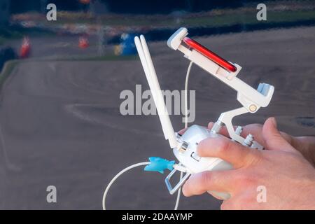 Close up of drone pilot hands controlling aircraft with remote control transmitter outdoors Stock Photo