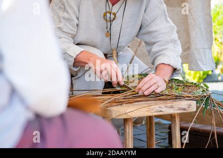 Close up of craftsman wearing rural clothes making wicker basket Stock Photo
