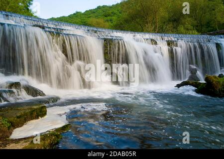 Spectacular waterfall on the River Wye in the beautiful Monsal Dale in Derbyshire, UK. Stock Photo