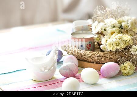 Easter composition with eggs, candle and flowers on the table close up. Stock Photo