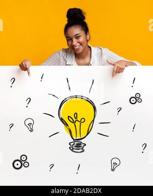 Happy black woman pointing at banner with drawing of light bulb, gears and question marks Stock Photo