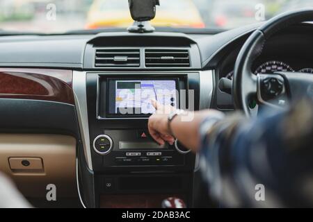 Woman driving car with hand touching navigation on monitor screen. Stock Photo