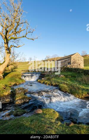 cray lower falls with barn and moon in wharfedale yorkshire on sunny day with blue sky vertical Stock Photo