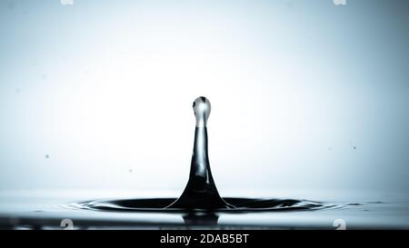 Close-up of a water drop falling on water surface Stock Photo