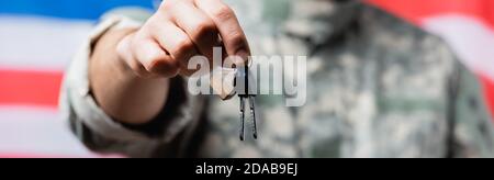 partial view of patriotic military man holding keys near american flag on blurred background Stock Photo